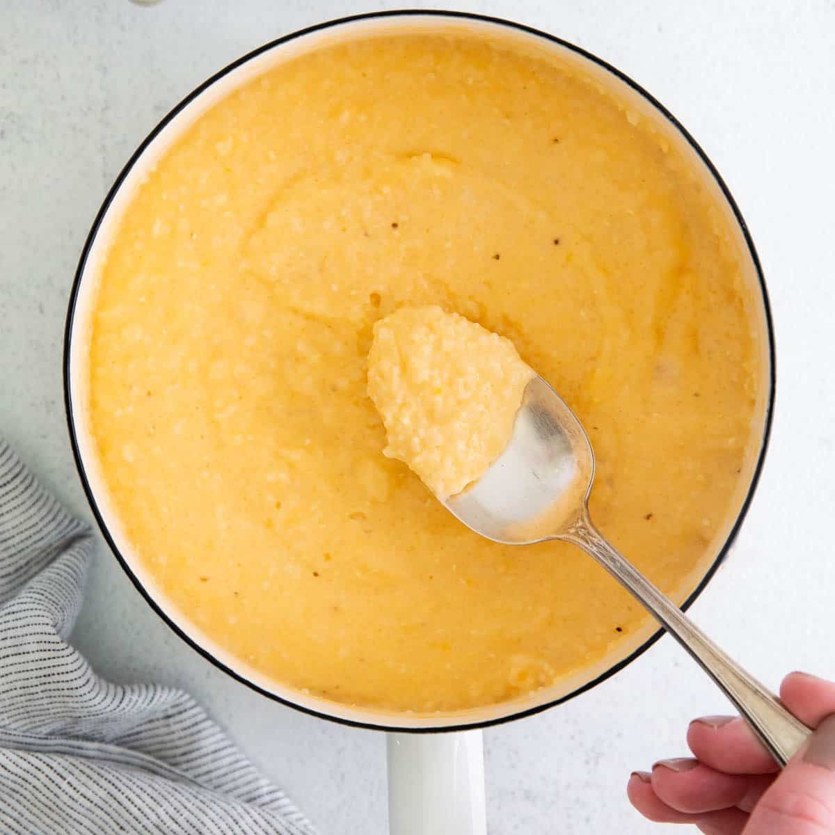 Cream cheese grits in a pot with a spoon