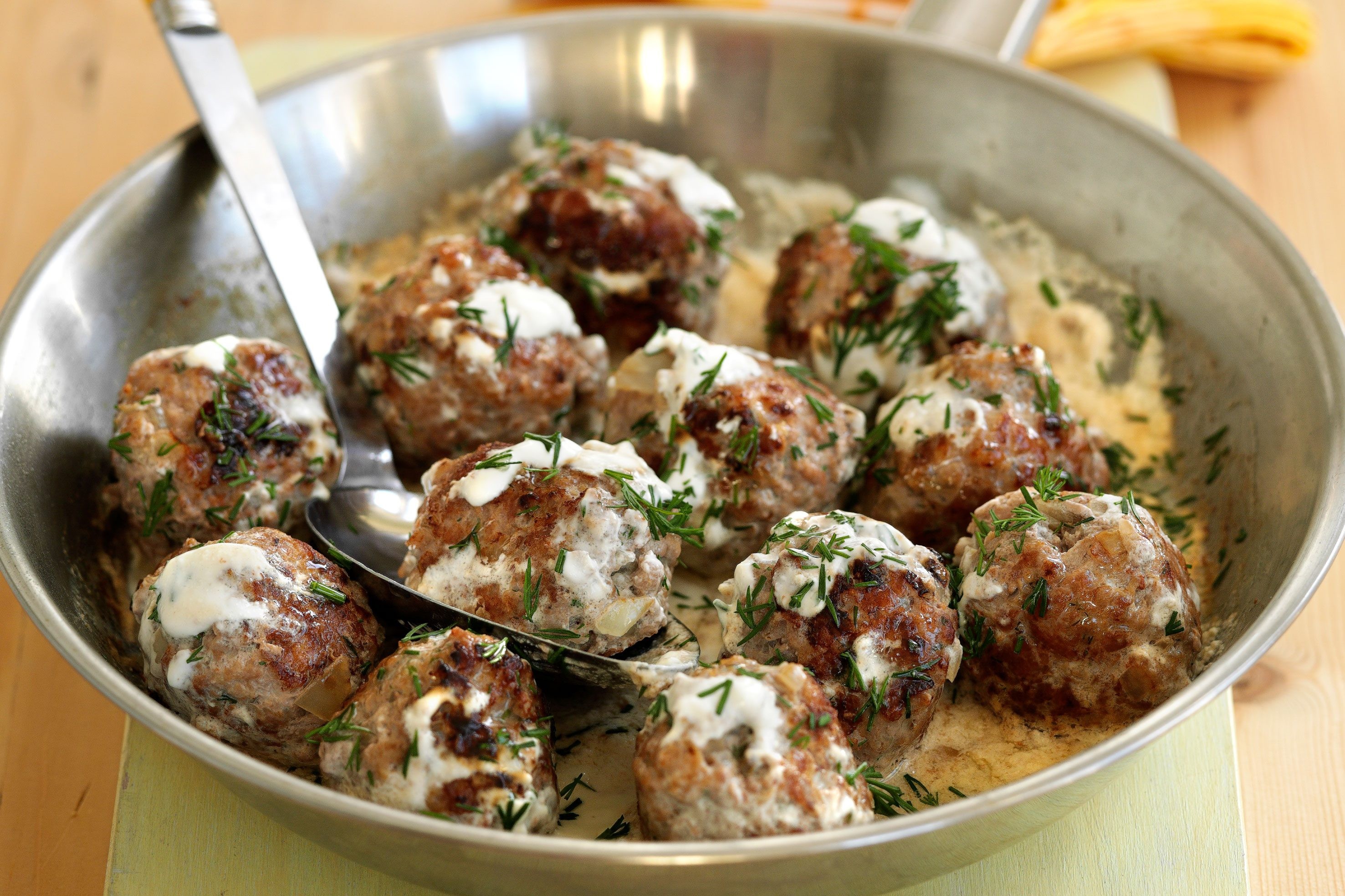 Pan of Swedish meatballs covered in sauce and herbs. Swedish meatballs with sauce and herbs in a pan.