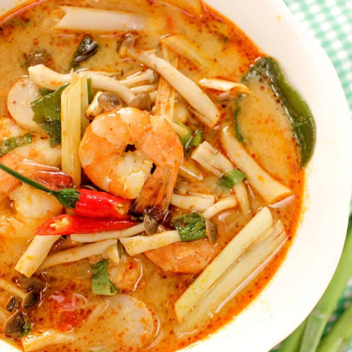 A bowl of tom yum soup with shrimp, mushrooms, lemongrass and chilies