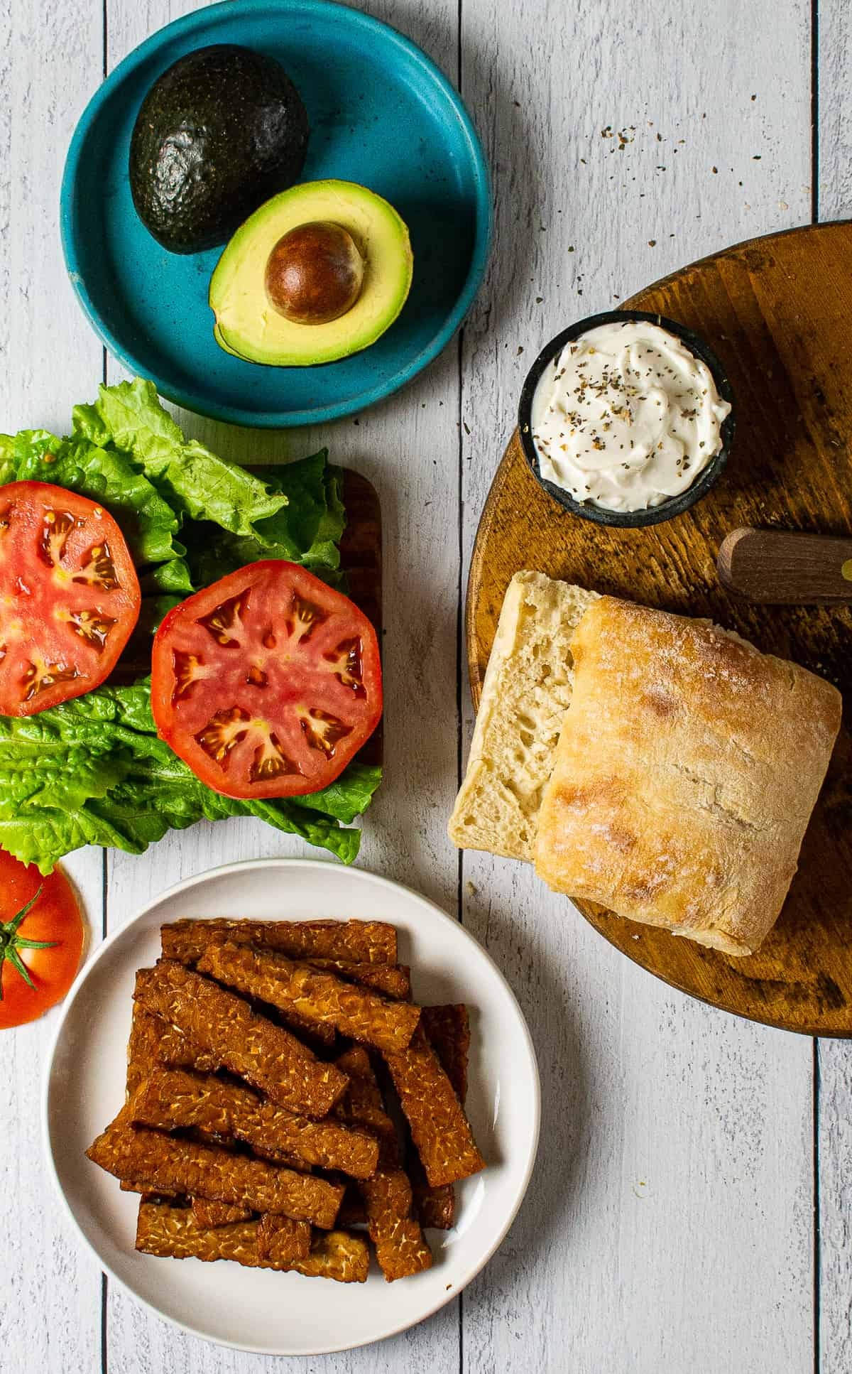 A vegan BLT sandwich with plant-based bacon, lettuce, tomato, and vegan mayo on toasted bread.