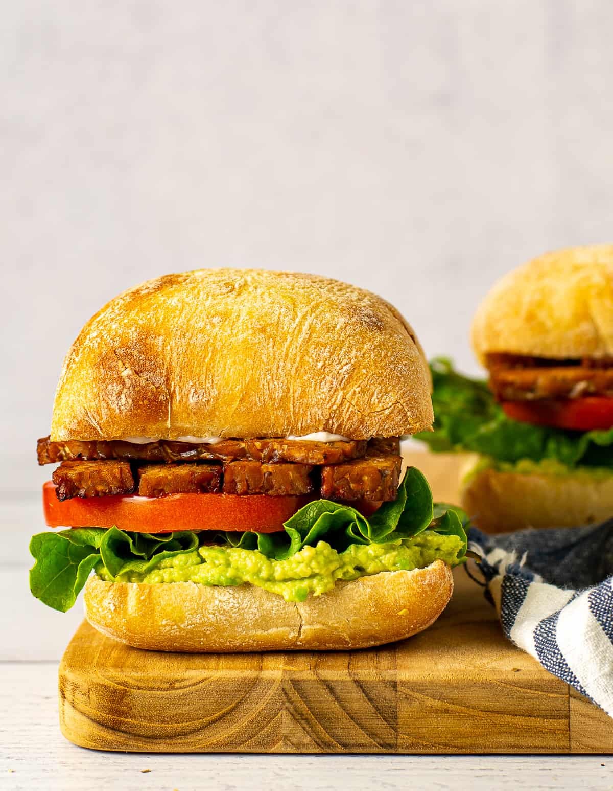 Close-up of a TTLA sandwich, showcasing the layers of tempeh, tomato, lettuce, and avocado.
