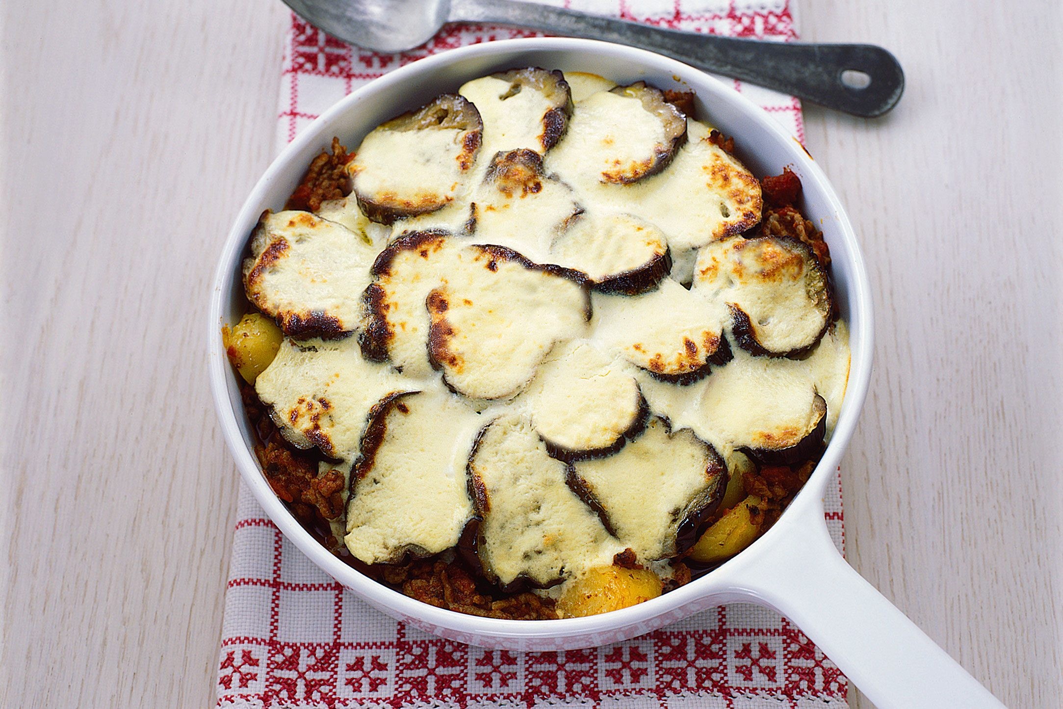Aubergines in a skillet pan covered in bechemel sauce