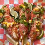 Elote Corn Dog at a county fair, topped with mayo, Hot Cheeto dust, Parmesan, and cilantro.