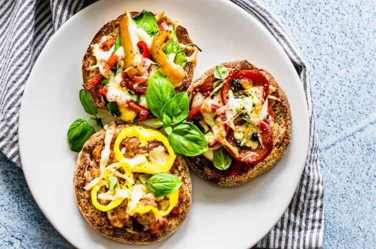 English muffin pizzas being served on a white plate.