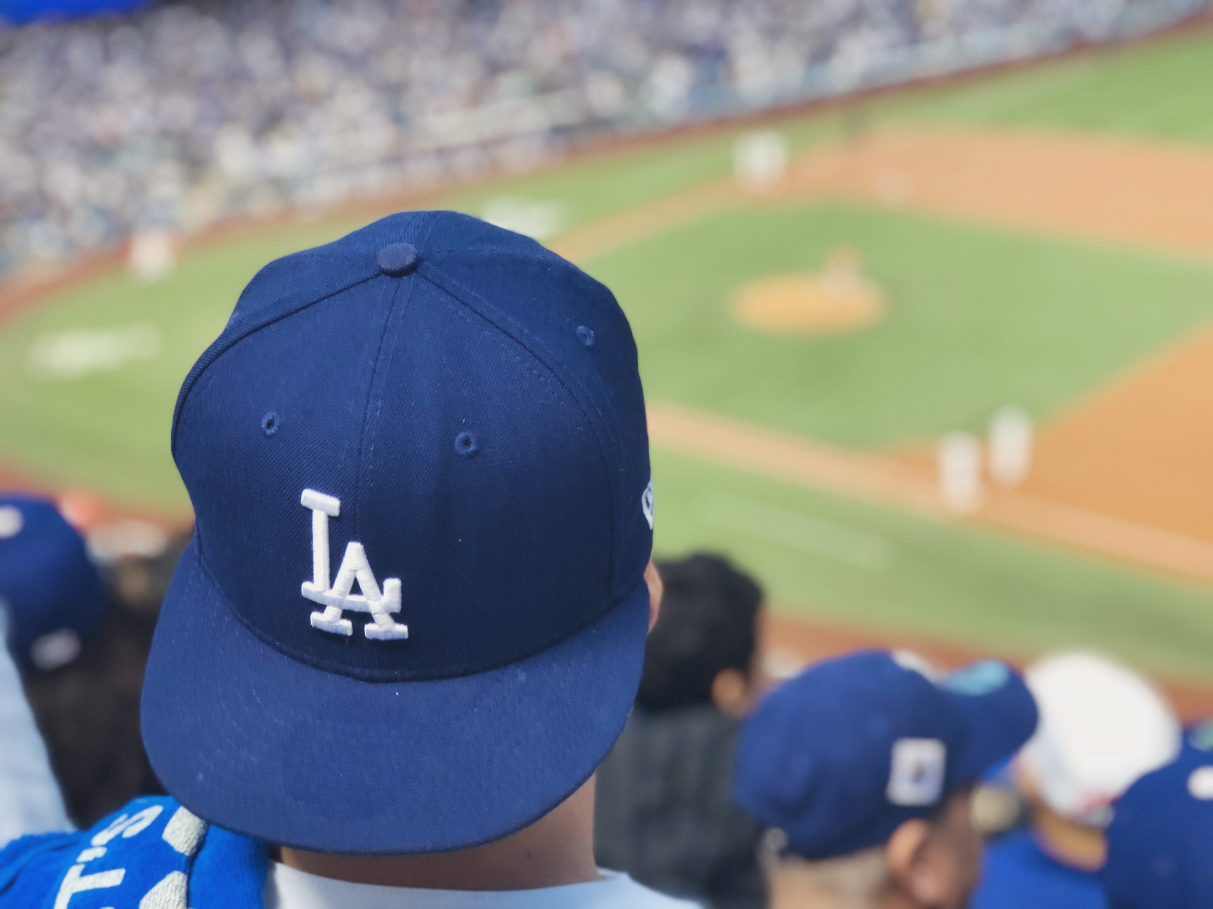 A fan shows their support for the Los Angeles Dodgers with a ball cap while sitting in stands. A Dodgers fan wearing a team cap enjoys the game from the stands, embodying the spirited atmosphere of Dodger Stadium