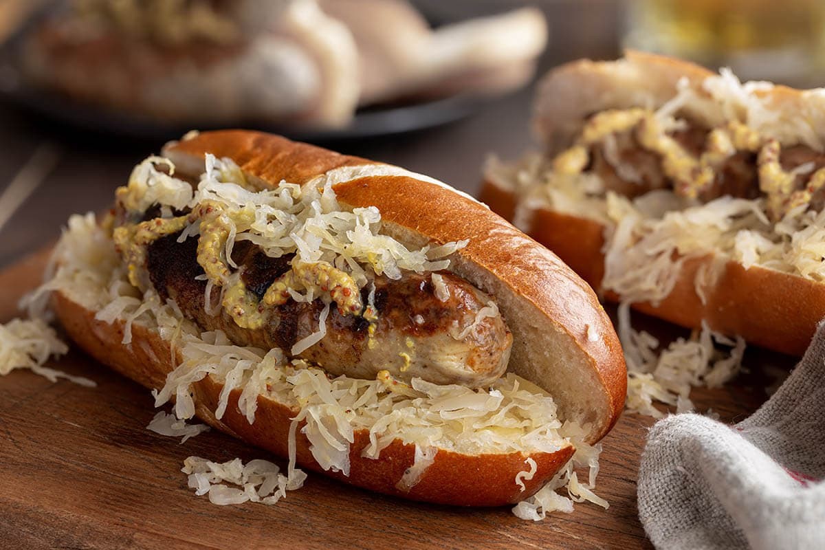 Grilled bratwursts on a rustic wooden board with various toppings like mustard, sauerkraut, and onions, creating an inviting and flavorful presentation perfect for a summer barbecue, enhancing the theme of pairing bratwursts with complementary foods for an enjoyable culinary experience