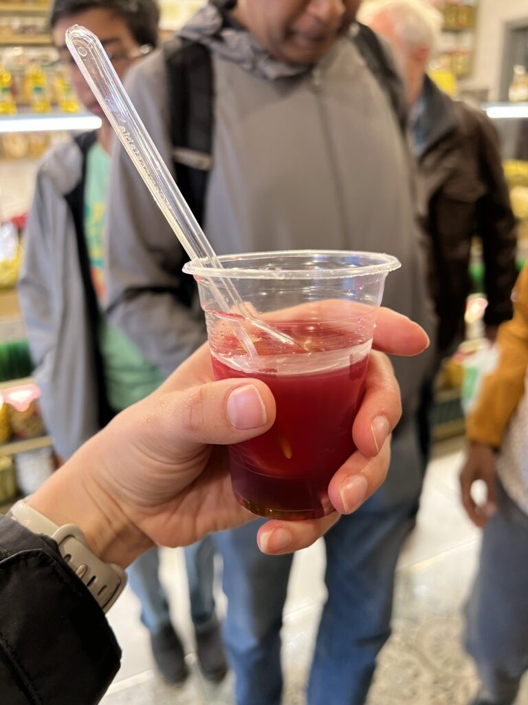 A glass of Turşu Suyu, a bright pink pickle juice made with pickled cucumber and cabbage