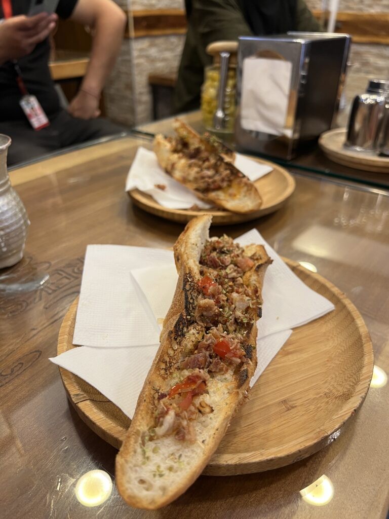 A Kokoreç sandwich, grilled lamb intestines and offal seasoned with spices, served in a bread roll