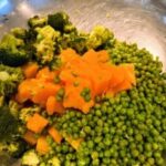 Prepared ingredients like broccoli, carrots, and peas for homemade dog food.