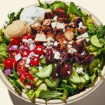 Cava's Greek salad features a base of romaine and arugula, with grilled chicken, tzatziki, feta, cucumber, tomato, Kalamata olives, and Greek vinaigrette.