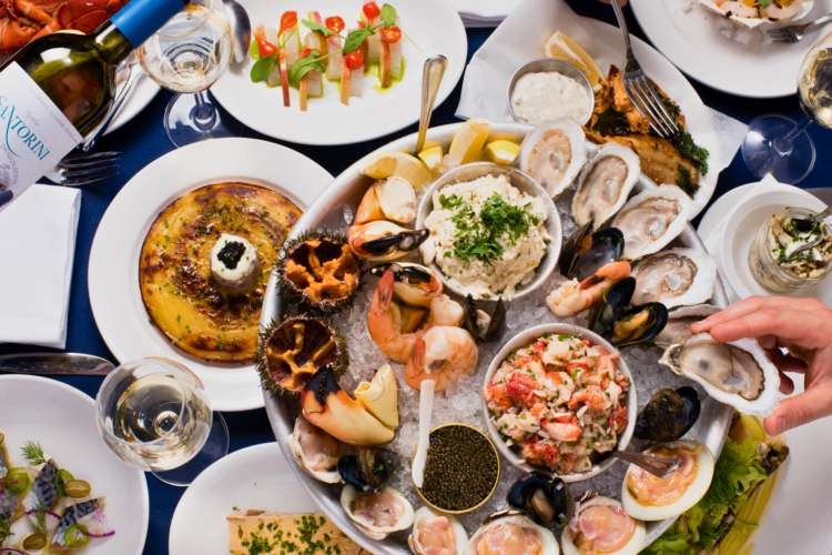 Neptune Oyster table covered in Boston seafood like oysters, lobster, crab claws, etc.