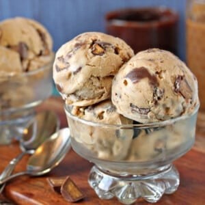 Several scoops of Peanut Butter Cup Ice Cream in a glass dessert bowl next to silver spoons.