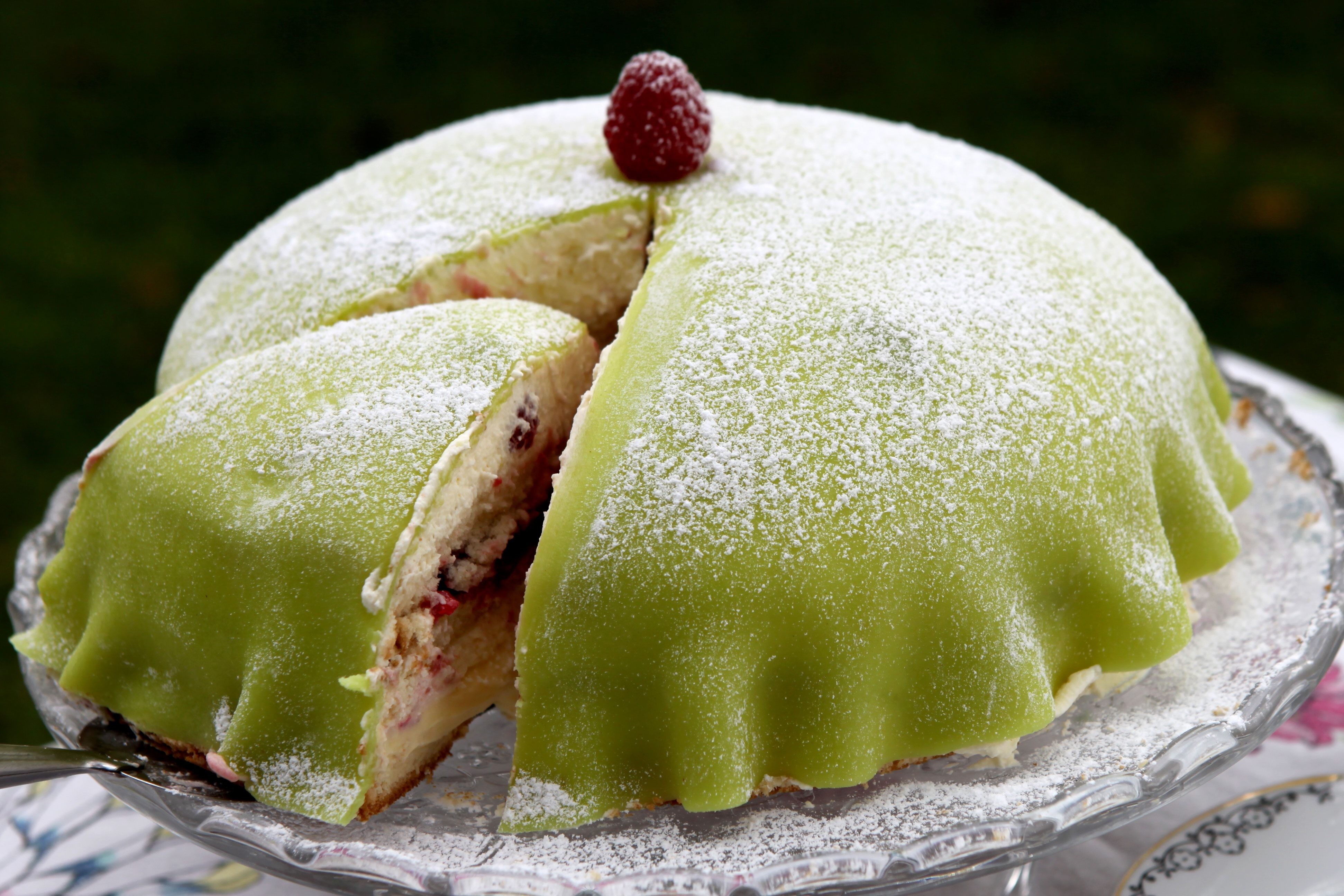 Layered cake with green icing and a raspberry on top. Green layered cake with raspberry on top.