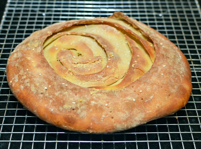 A serving of Qurutob, featuring torn bread, qurut sauce, and fresh vegetables