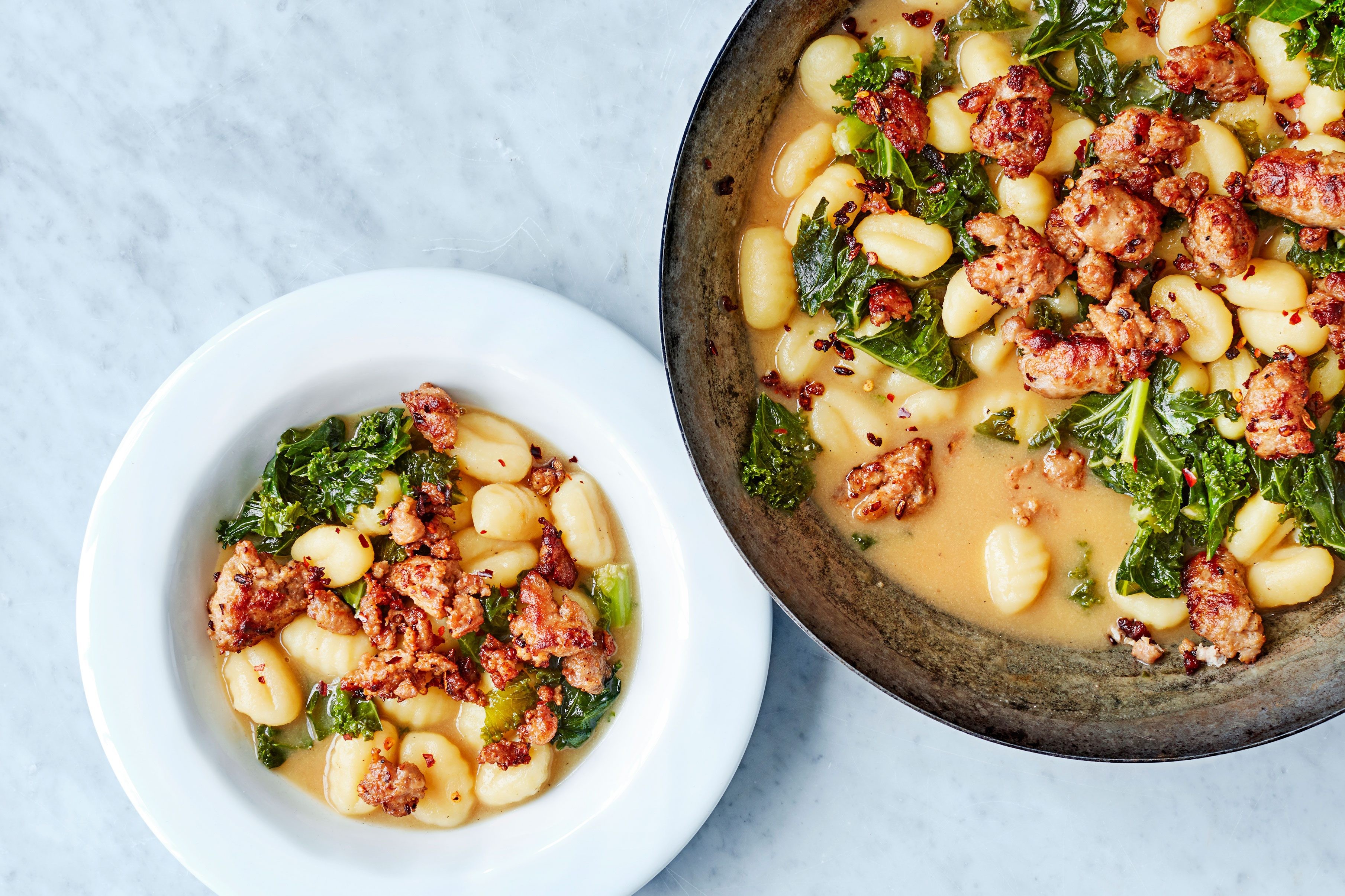 Gnocchi, sausage and kale in a pan and bowl
