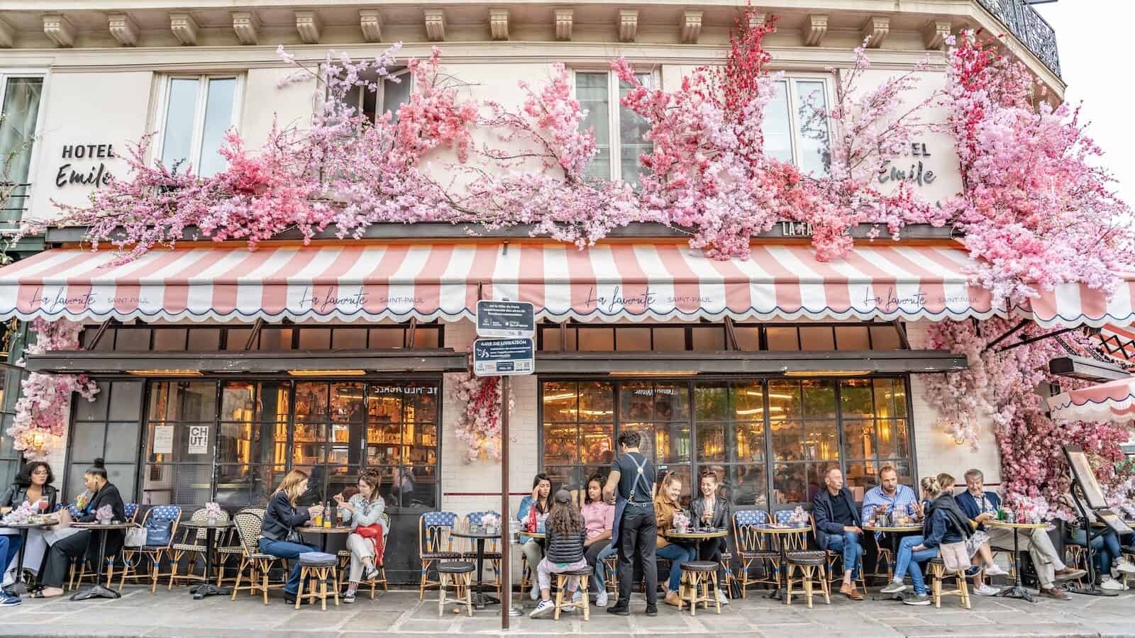 People enjoying a meal at a traditional cafe in Paris, France, surrounded by spring decor, reflecting the leisurely pace and appreciation for gastronomy in French culture