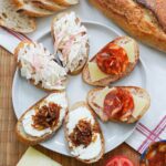 Three diverse Spanish pintxos featuring bread, cheese, tomato, and chorizo, showcasing the variety of toppings