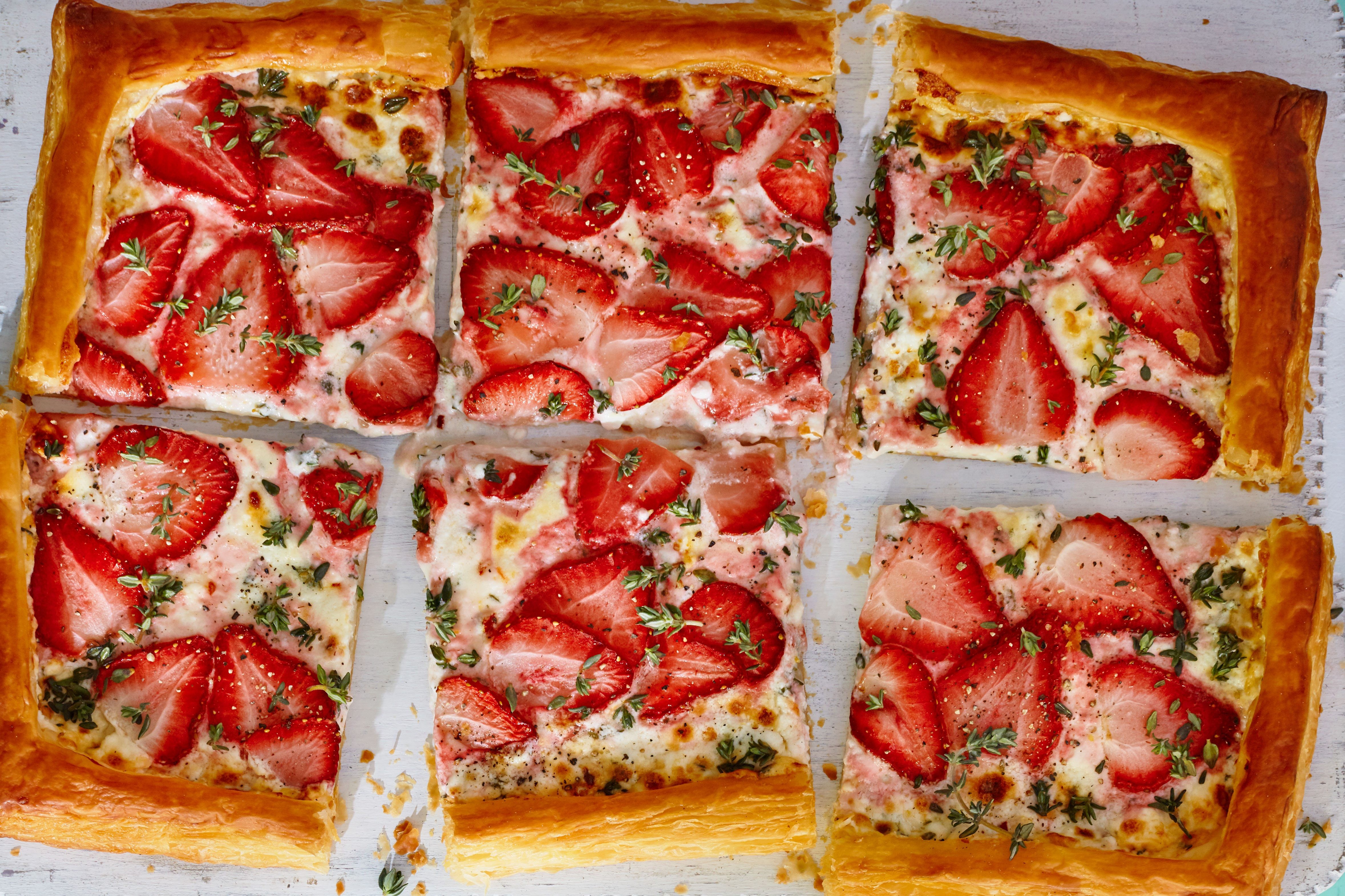 Tart topped with strawberries and cut into six slices. A strawberry tart with six slices cut out.