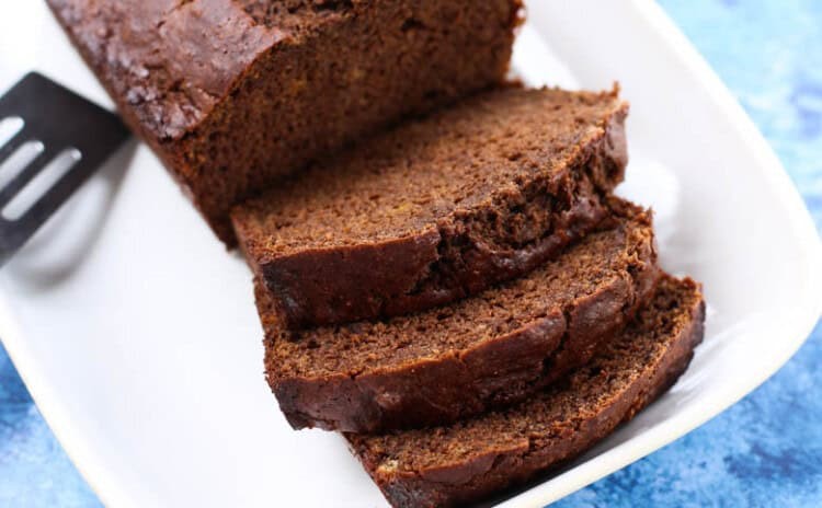 Chocolate banana bread on a white plate with a few slices cut.