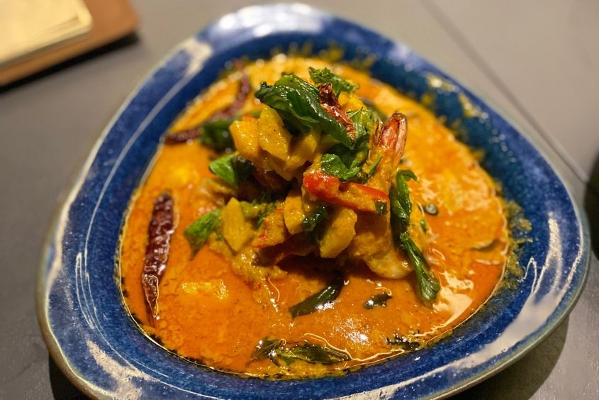 Overhead shot of a Thai curry dish with various ingredients and spices visible.