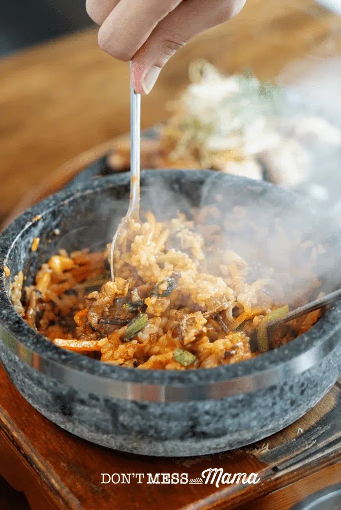 Korean dolsot bowl filled with rice, vegetables, and meat, steaming hot