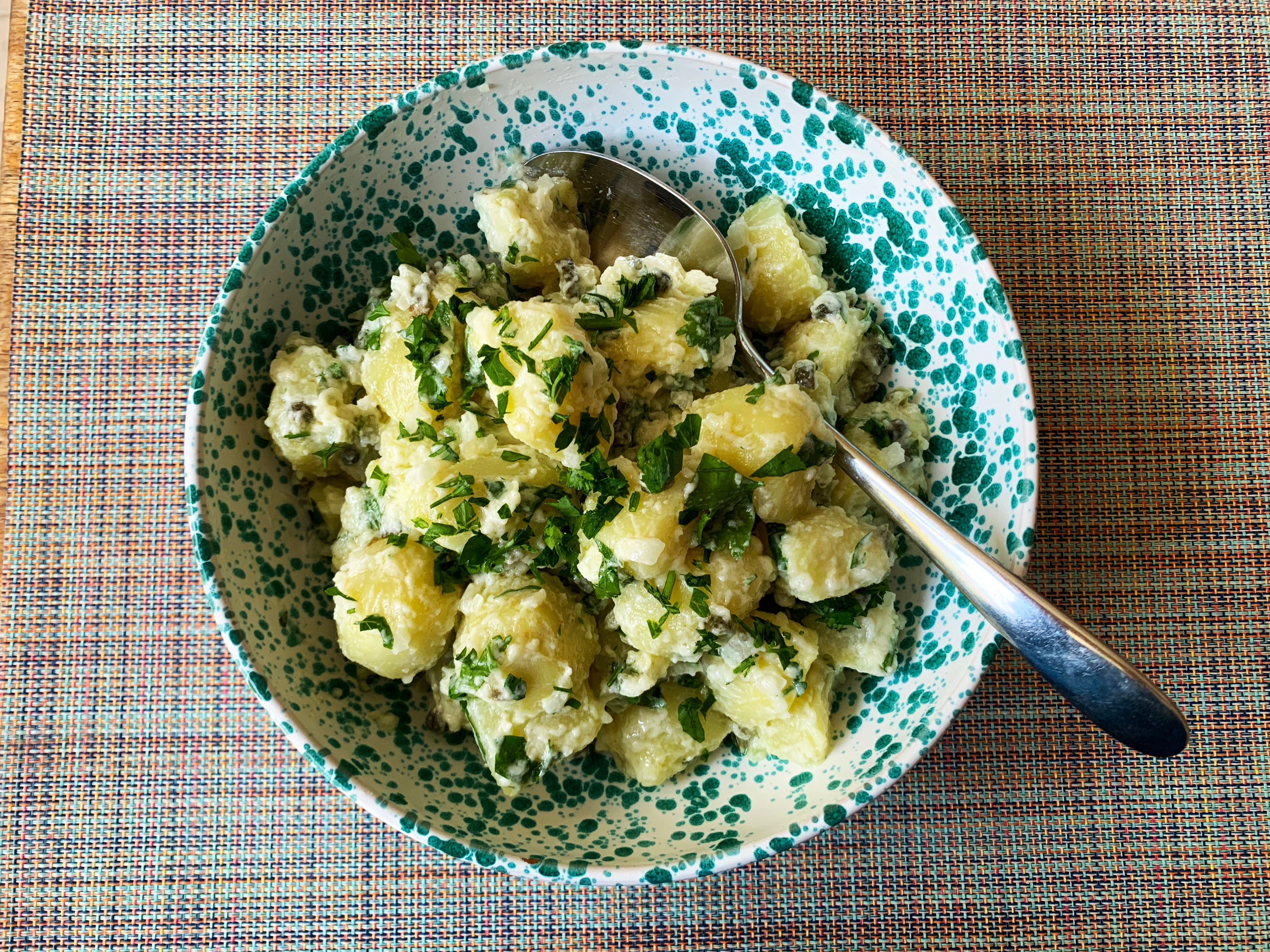Classic potato salad in a speckled bowl with silver spoon