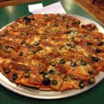 Close-up of St. Louis-style pizza with thin, crisp crust, Provel cheese, and square cut slices