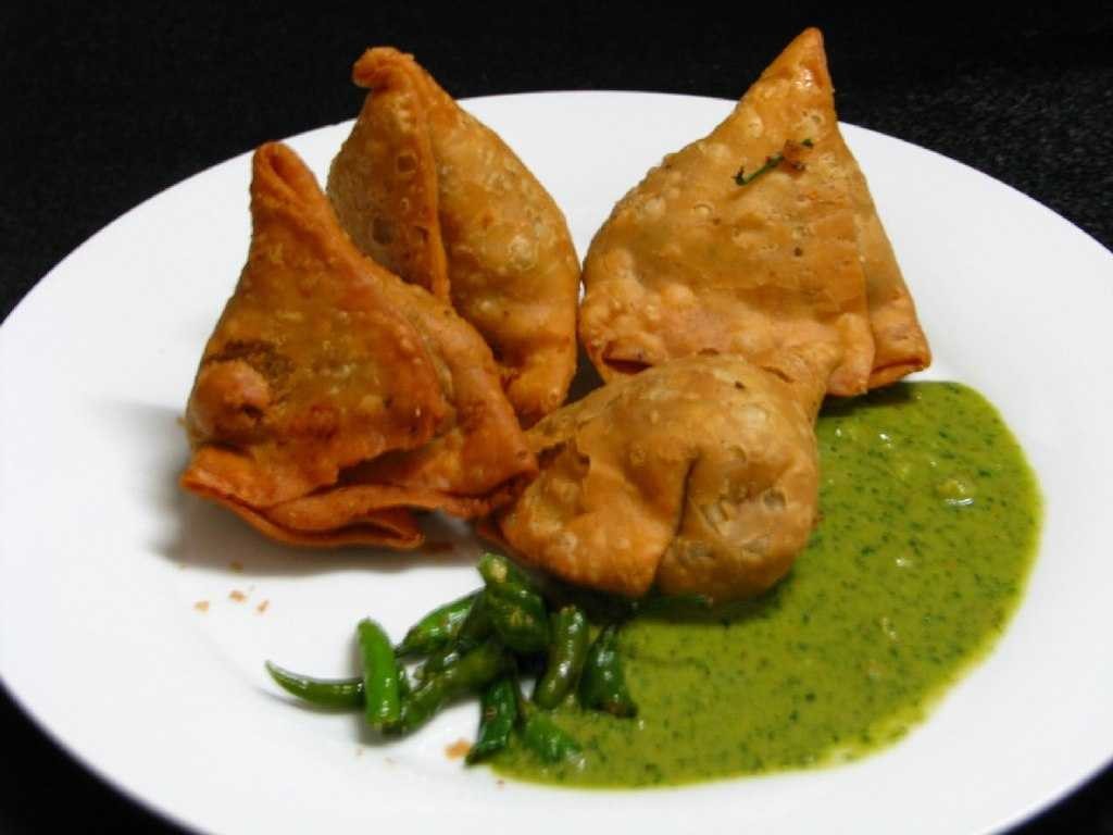 A plate of Nepali Samosa featuring a spicy dish, served with a sweet red colored Chutney