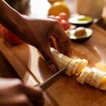 A close-up of a hand peeling a ripe yellow banana, showcasing its soft texture