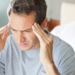 Man holding his head with a headache, indicating potential health risks from consuming too much spam