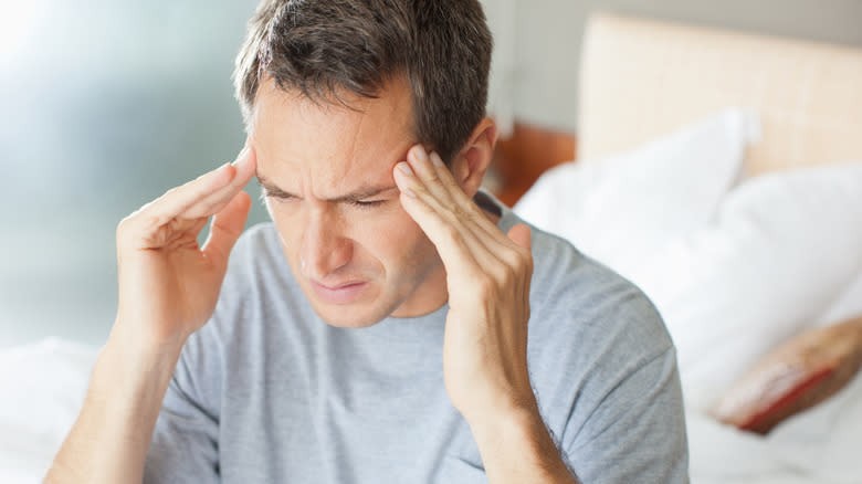 Man holding his head with a headache, indicating potential health risks from consuming too much spam