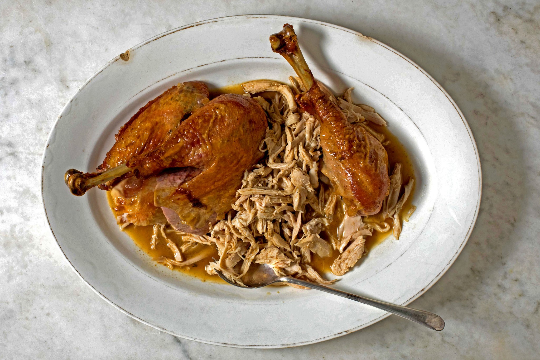Overhead shot of sliced smoked turkey on a wooden cutting board, garnished with herbs and cranberries.