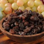 Raisins and grapes in a wooden bowl, showcasing the natural sweetness and versatility of this dried fruit.