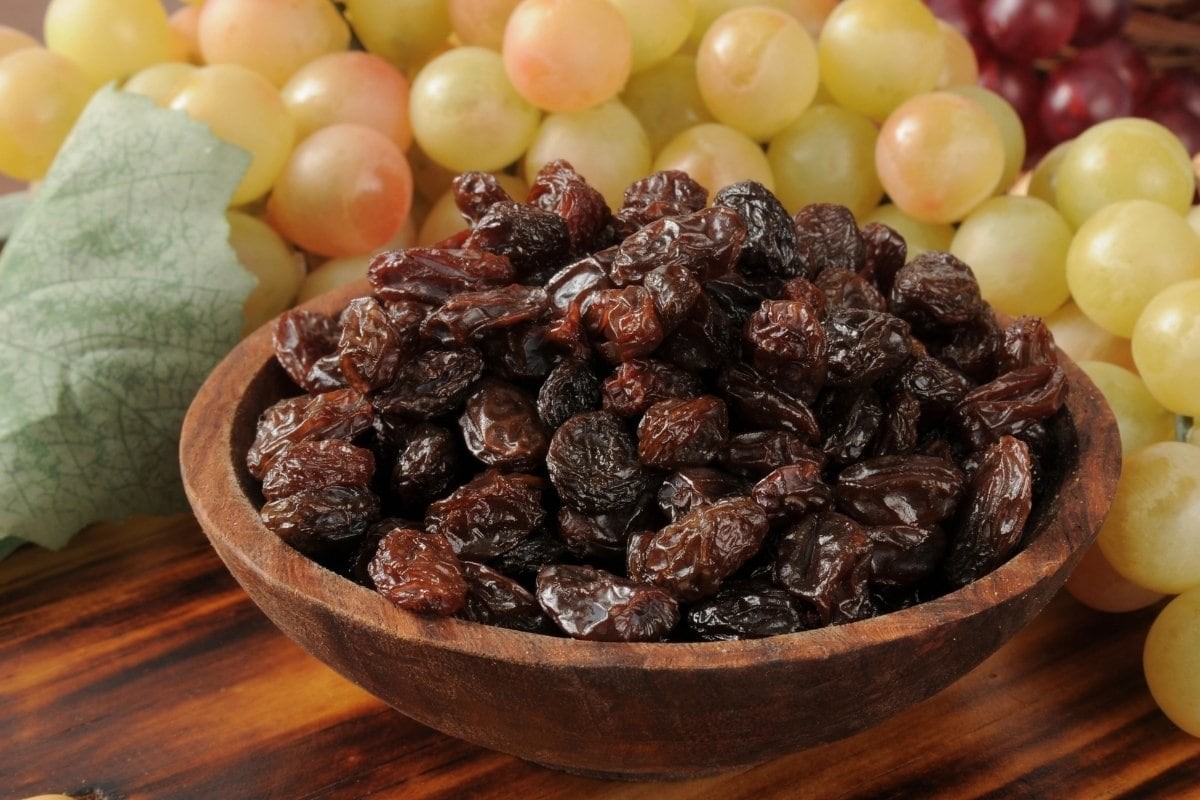 Raisins and grapes in a wooden bowl, showcasing the natural sweetness and versatility of this dried fruit.