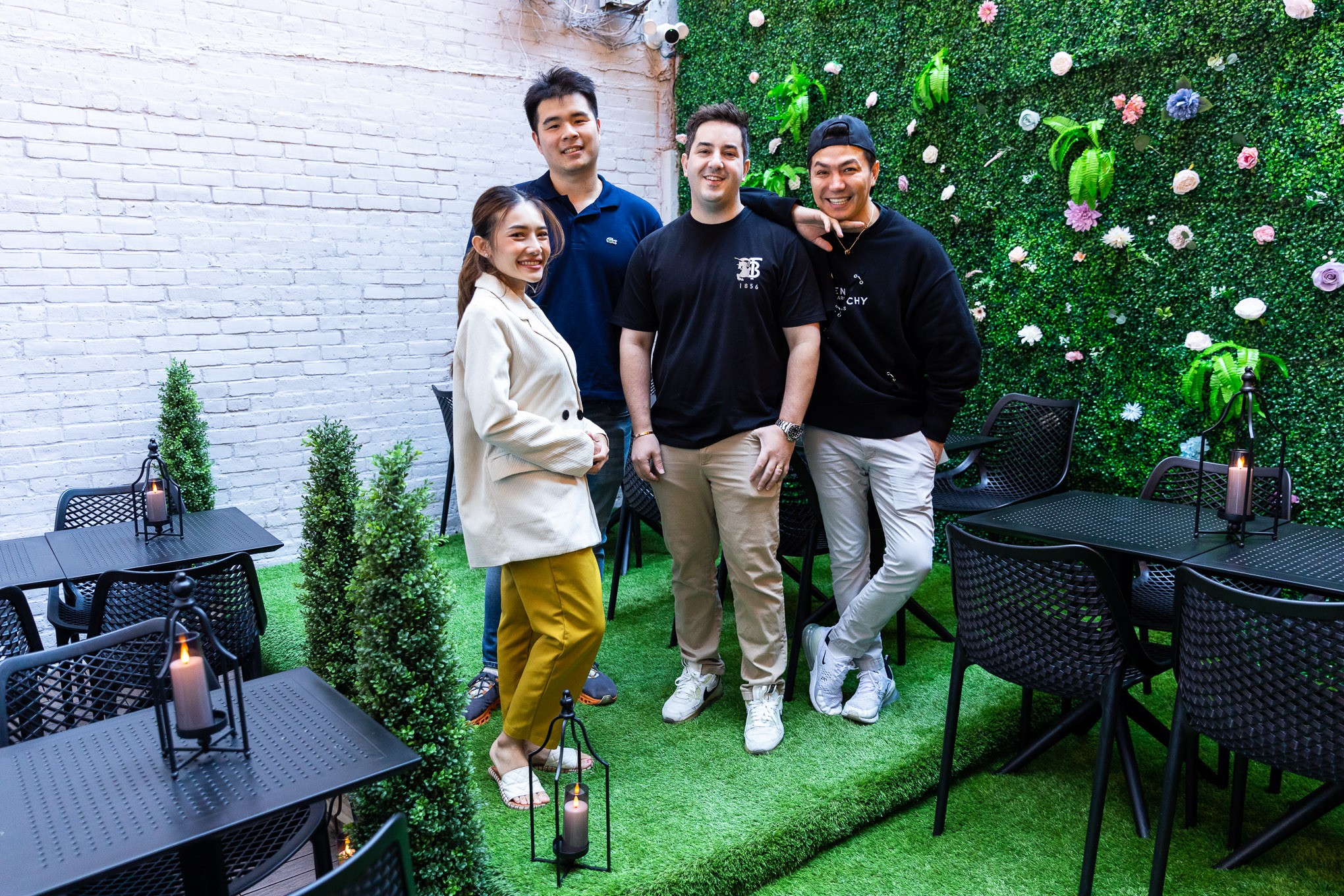 The four owners of Thai Food Near Me stand in the outdoor patio area of the restaurant.