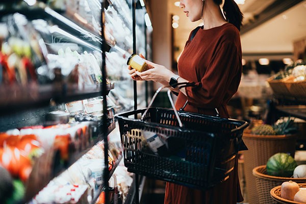 Woman in a grocery store carefully reading a product label