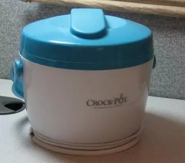 The metal insert with the plastic lid contains the food ready to heat.