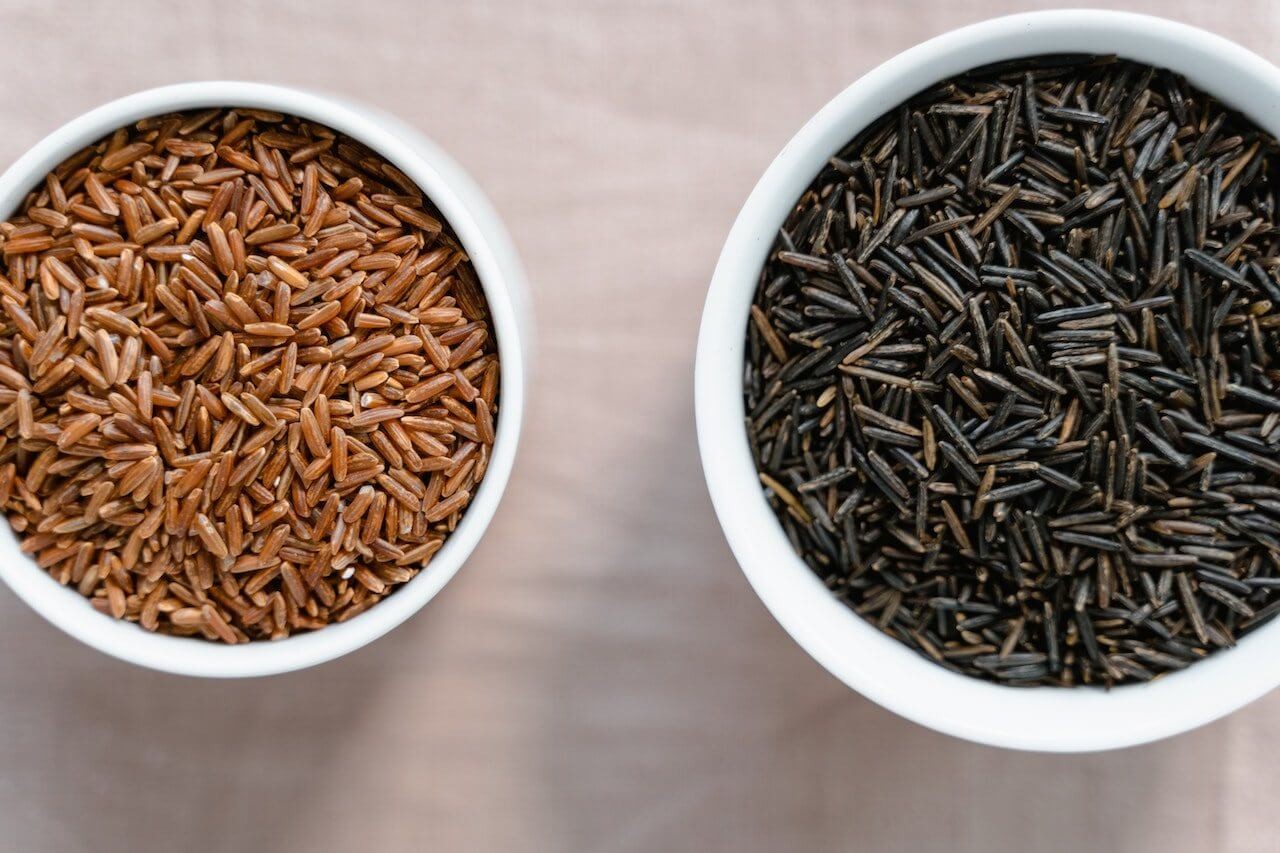 Bowls of brown and black rice, showcasing healthier options for weight loss.