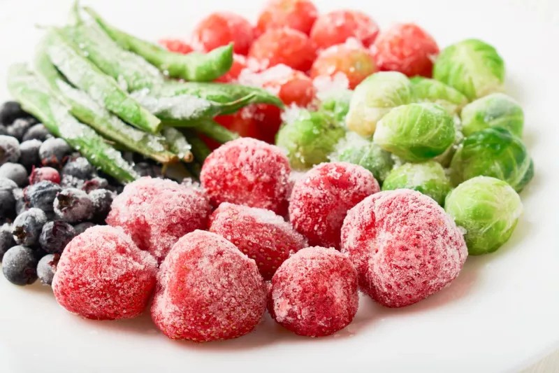 Frozen strawberries, brussels sprouts, green beans on a white plate