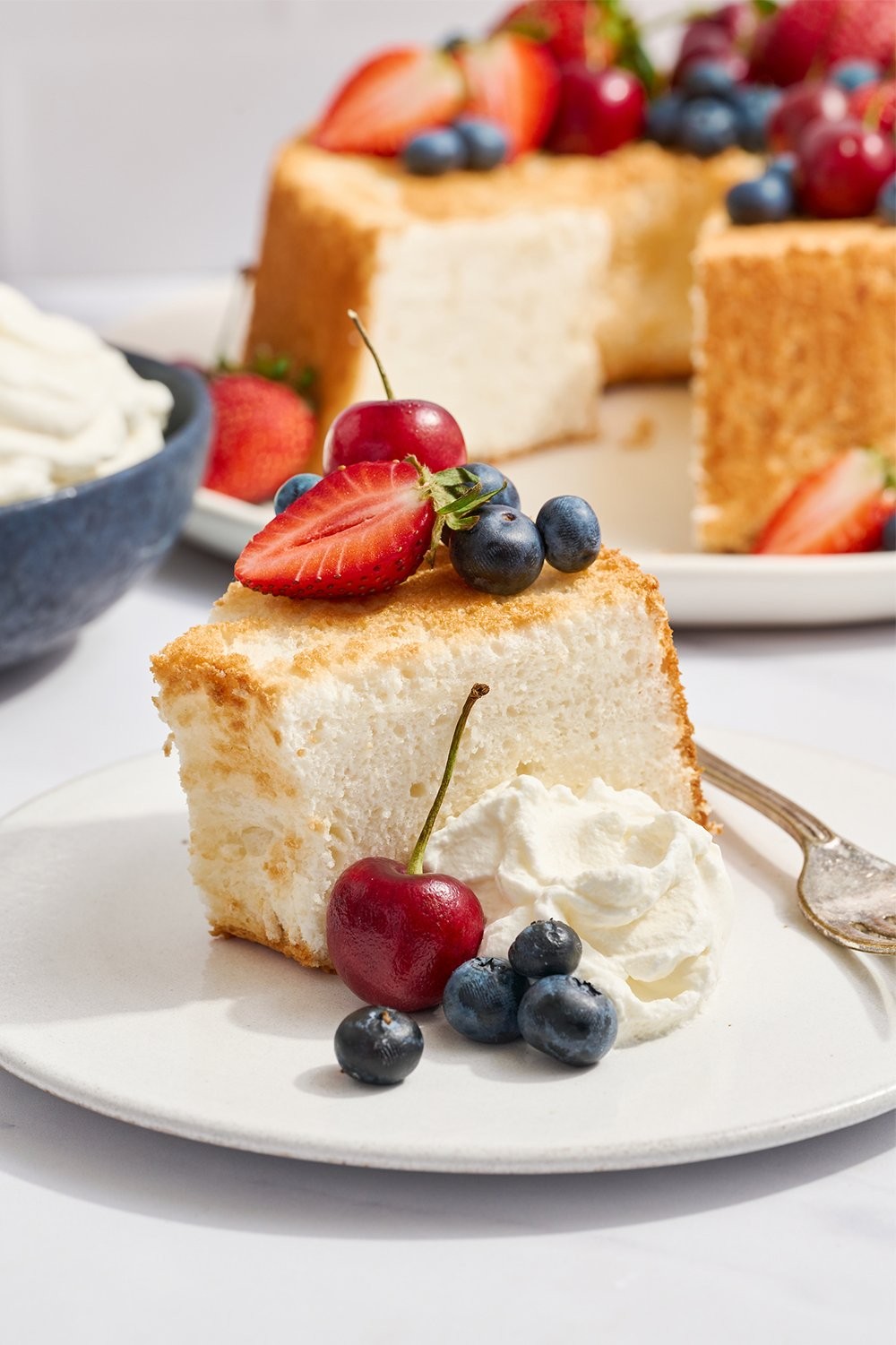 Slice of cake on a plate with whipped cream and berries