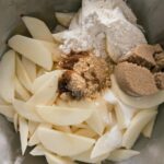 Apple slices being mixed together with spices and sugars for apple cobbler.