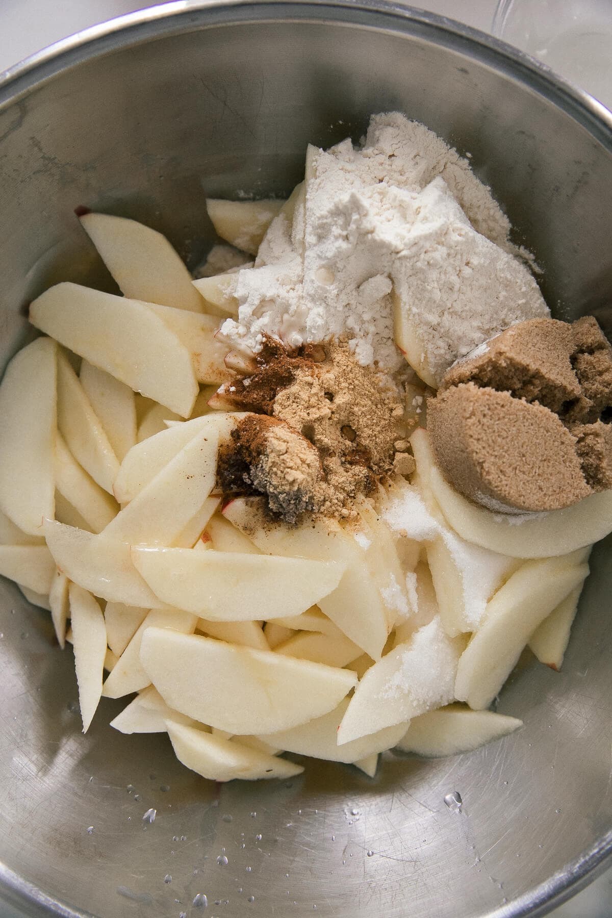 Apple slices being mixed together with spices and sugars for apple cobbler.
