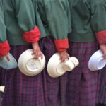 A line of students holding empty food bowls, symbolizing food shortages.