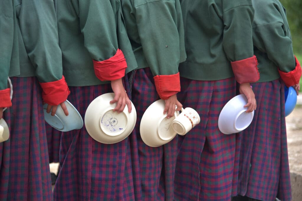 A line of students holding empty food bowls, symbolizing food shortages.