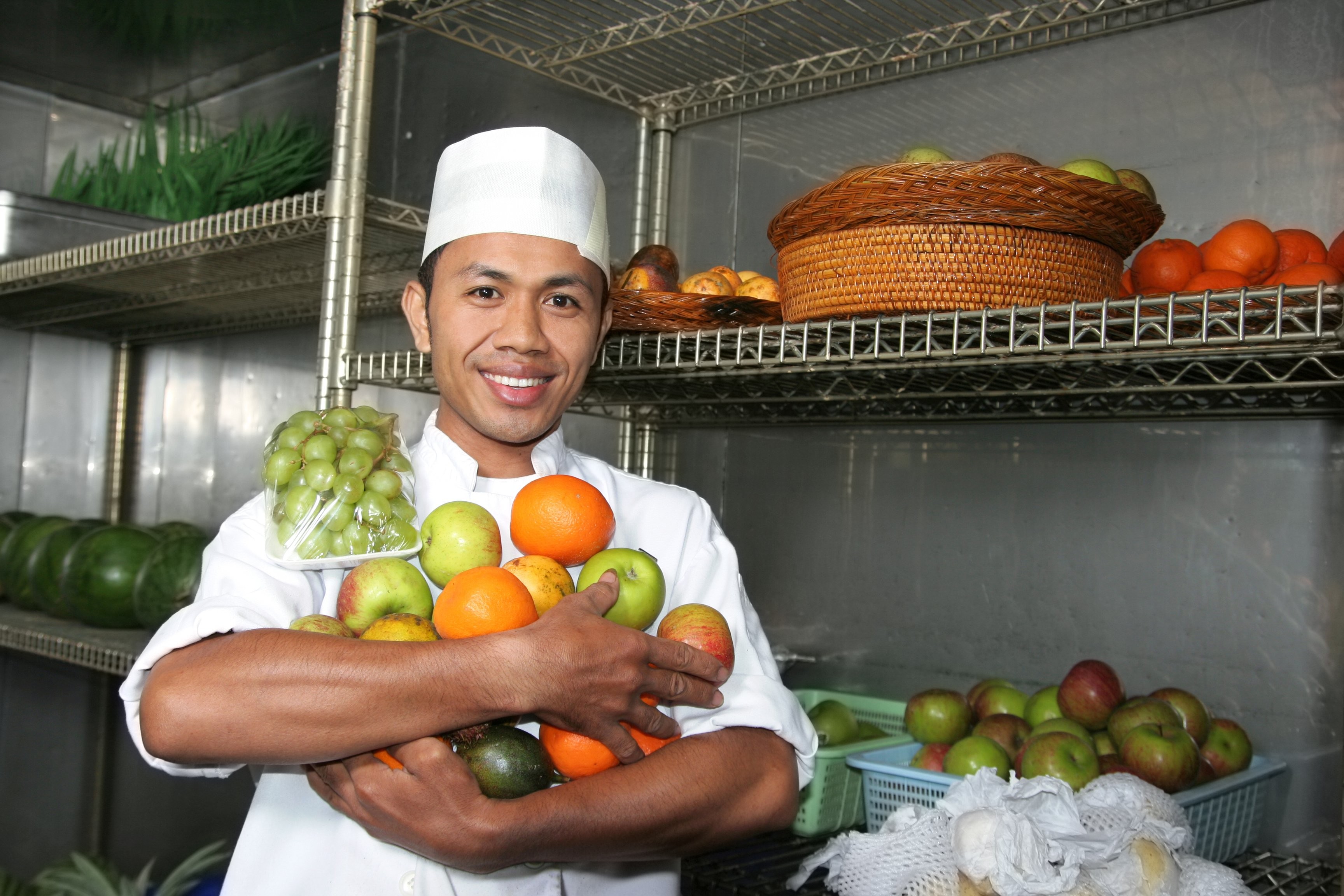 Chef placing fruits into a well organized storage shelf