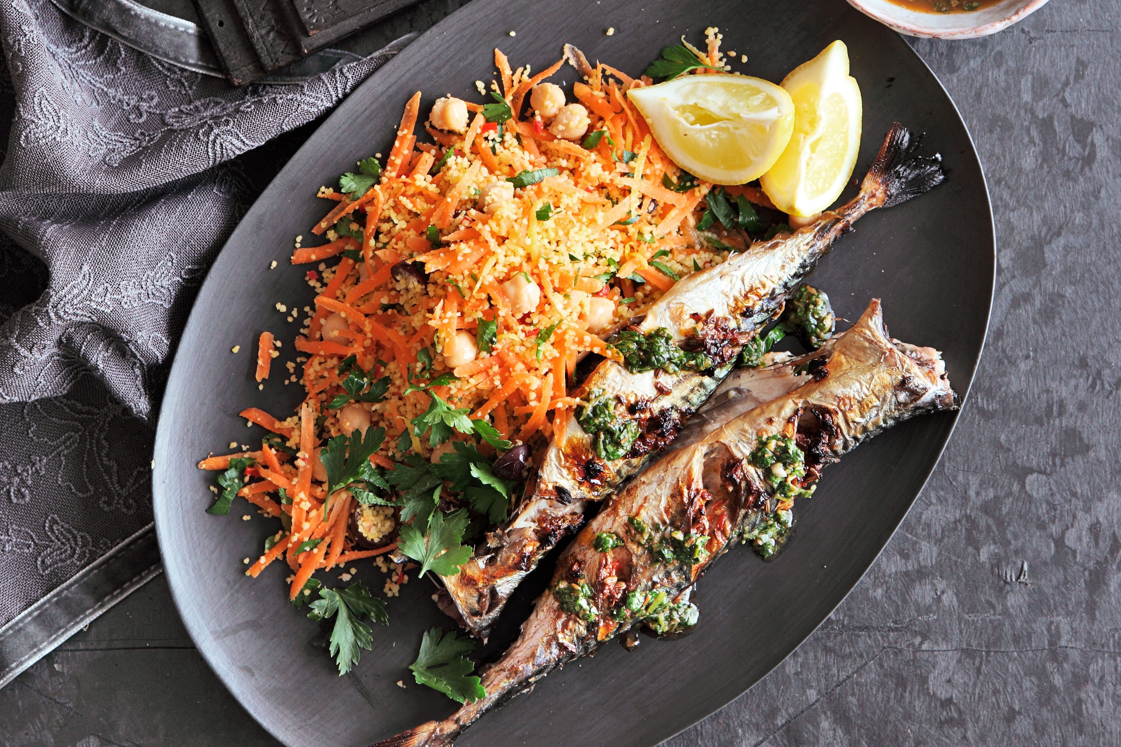 Grilled mackerel marinated in chermoula, served with grated carrot and lemon wedges, a vibrant and flavorful seafood dish.