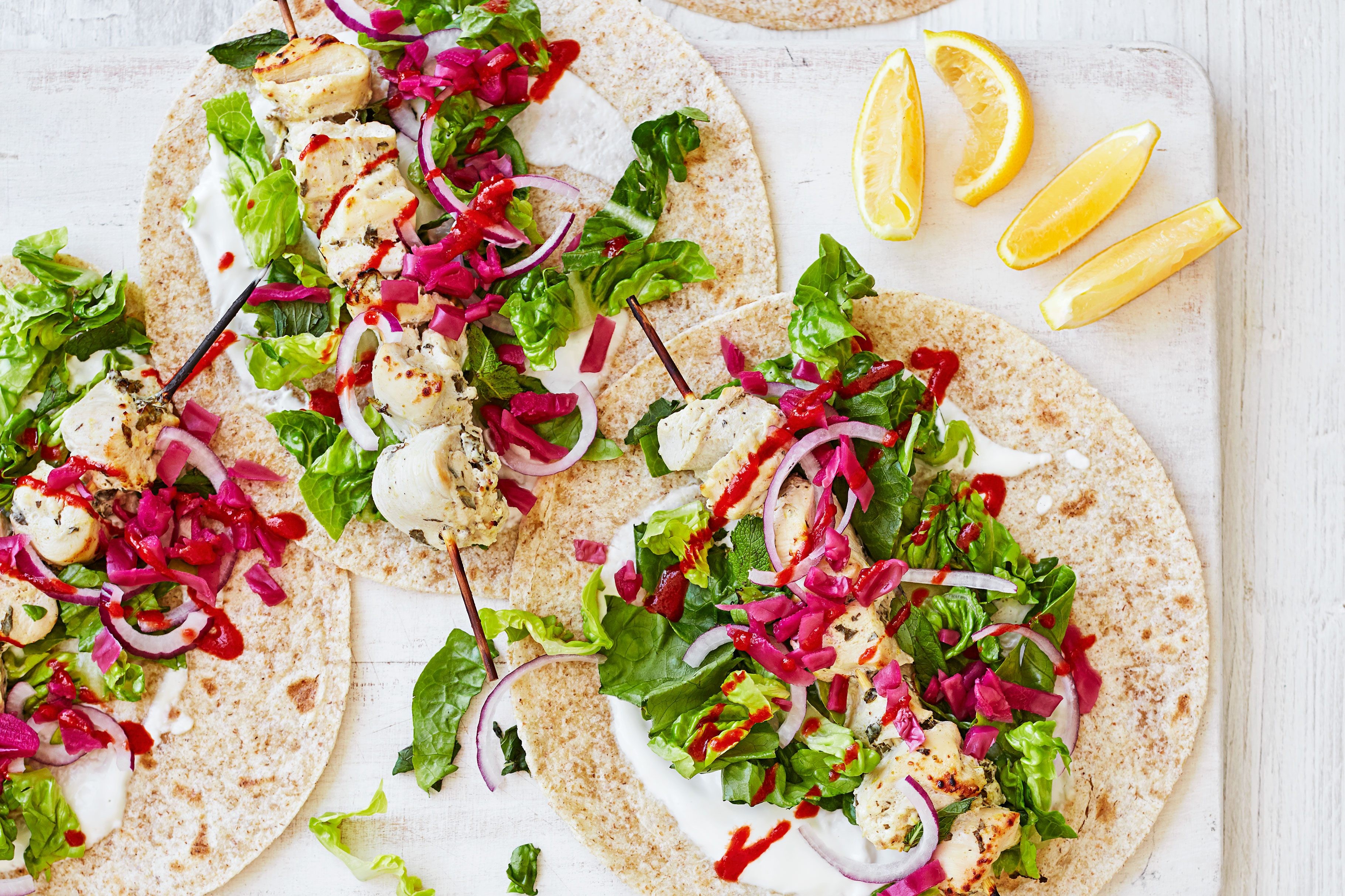 Chicken skewers and vegetables inside two wraps.