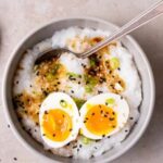 Classic Congee served with toppings like scallions and preserved duck egg, offering a comforting and nutritious start to the day