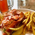 Lobster Roll on a plate with coleslaw and french fries