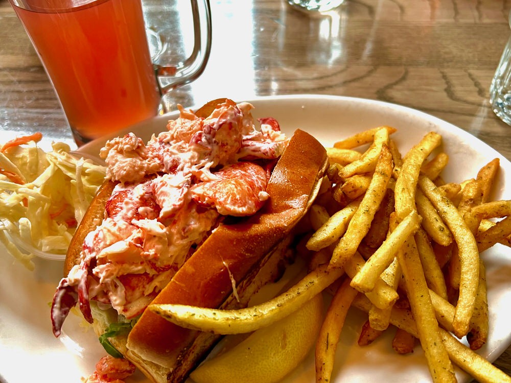 Lobster Roll on a plate with coleslaw and french fries